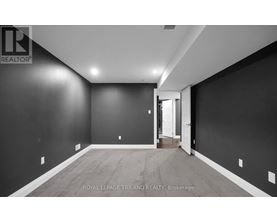A spacious room with dark walls and wooden flooring, with a doorway leading to another room.