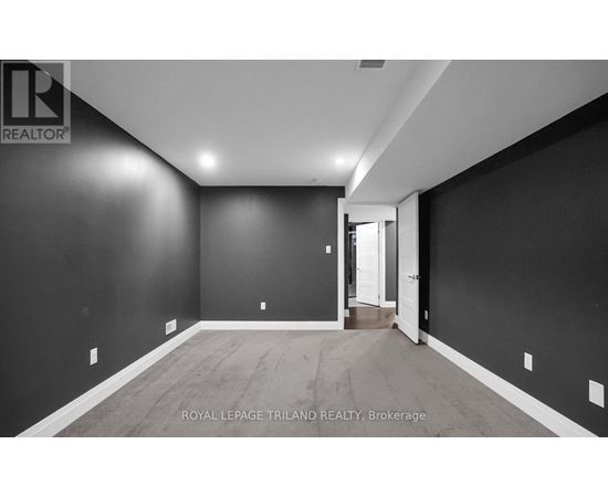 A spacious room with dark walls and wooden flooring, with a doorway leading to another room.