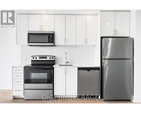 A modern kitchen with a black refrigerator, white cabinets, and a black stove top oven.