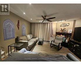 A living room with a ceiling fan and a person lying on the floor.
