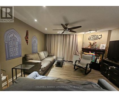 A living room with a ceiling fan and a person lying on the floor.