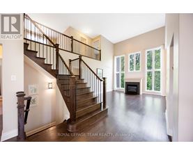 A spacious living room with a fireplace and a staircase.