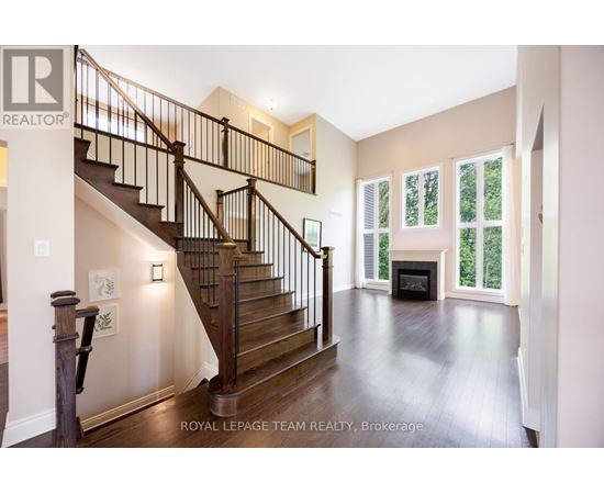 A spacious living room with a fireplace and a staircase.