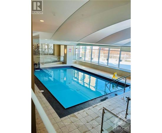A large indoor swimming pool with a glass barrier.