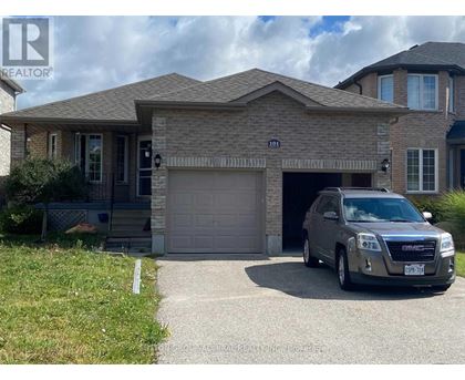 A grey SUV is parked in front of a house with a garage.