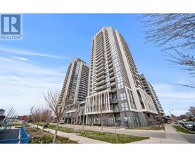 A tall residential building with a glass facade stands in front of a blue sky.