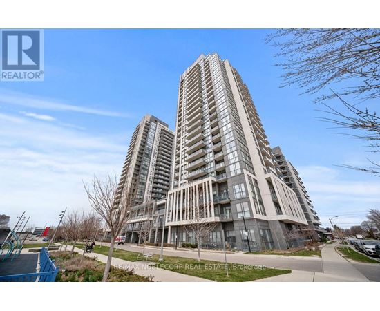 A tall residential building with a glass facade stands in front of a blue sky.