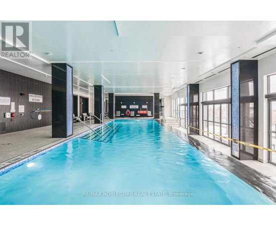A large indoor swimming pool with a blue tinted water.