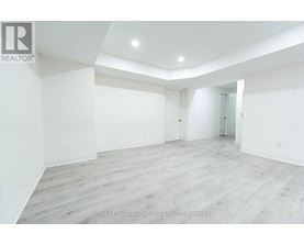 A spacious room with white walls and wooden flooring.