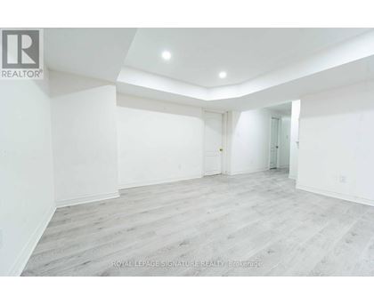 A spacious room with white walls and wooden flooring.