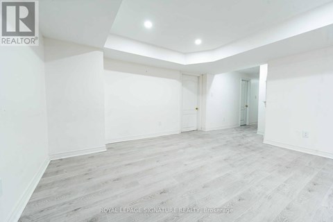 A spacious room with white walls and wooden flooring.