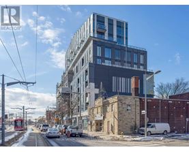 A modern building with a glass facade is under construction next to a red tram on a street.
