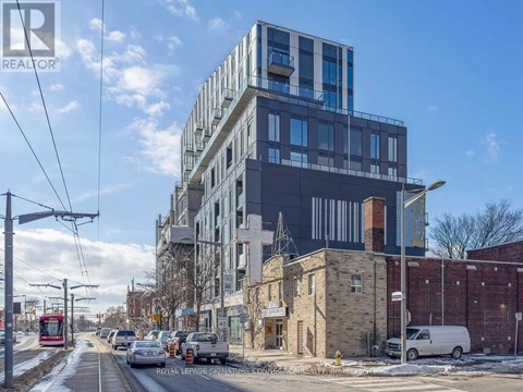 A modern building with a glass facade is under construction next to a red tram on a street.