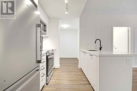 A modern kitchen with white cabinets and stainless steel appliances.
