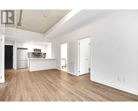A spacious, empty room with wooden flooring and white walls.