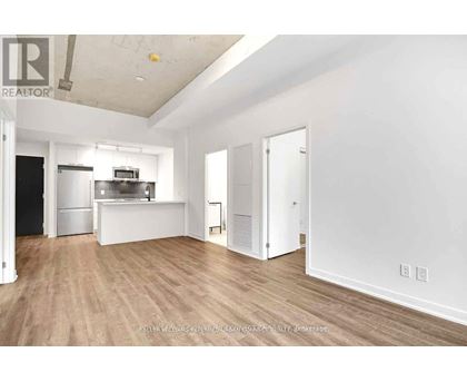 A spacious, empty room with wooden flooring and white walls.