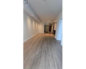 A spacious room with wooden flooring and white walls.