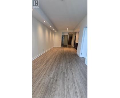 A spacious room with wooden flooring and white walls.