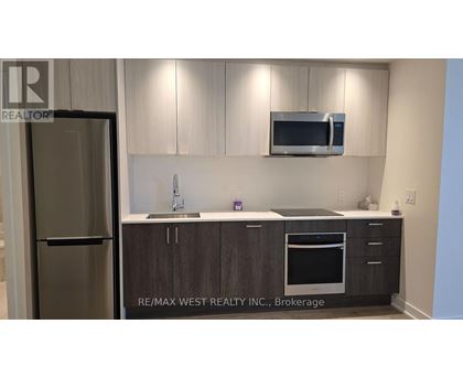 A kitchen with a refrigerator, microwave, and oven.