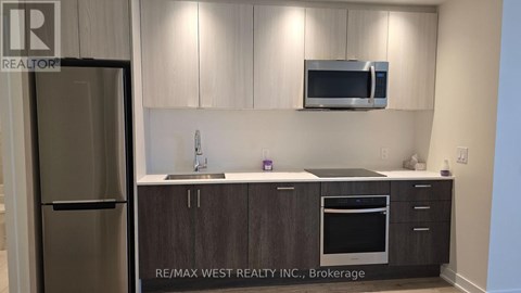 A kitchen with a refrigerator, microwave, and oven.