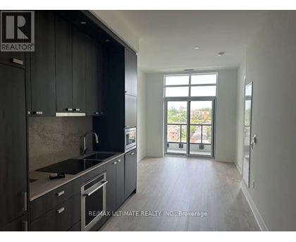 A modern kitchen with dark cabinets and stainless steel appliances.
