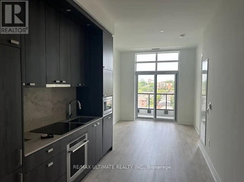 A modern kitchen with dark cabinets and stainless steel appliances.