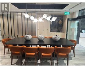 A dining room with a black table and orange chairs.