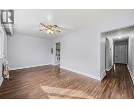 A spacious room with wood flooring and a ceiling fan.
