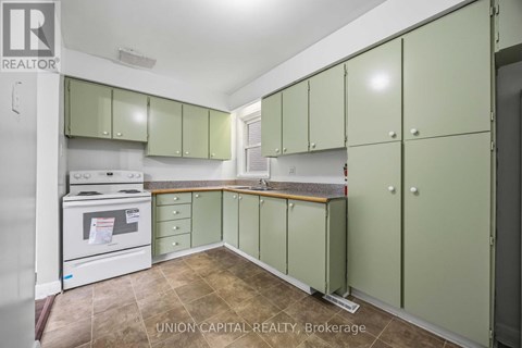 A kitchen with green cabinets and a white oven.
