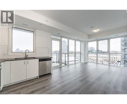 A spacious kitchen with white cabinets and a large window overlooking the city.