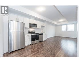 A modern kitchen with a stainless steel refrigerator and wooden flooring.