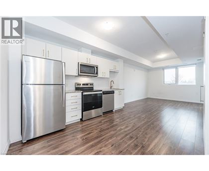 A modern kitchen with a stainless steel refrigerator and wooden flooring.