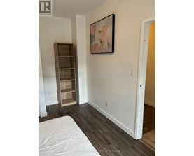 A bedroom with a bed, a shelf, and a painting on the wall.