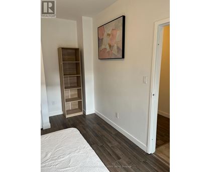 A bedroom with a bed, a shelf, and a painting on the wall.