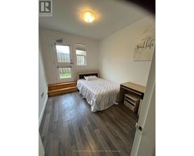 A bedroom with a bed, desk, and window.