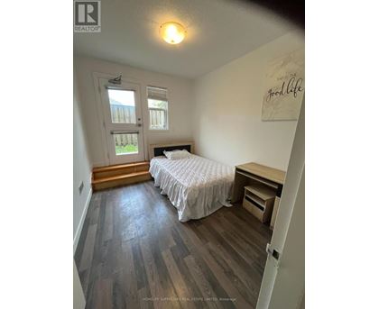 A bedroom with a bed, desk, and window.