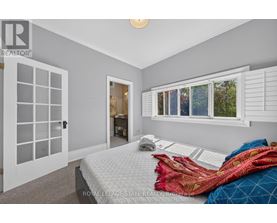 A bedroom with a bed, pillows, and blankets in front of a window with white shutters.