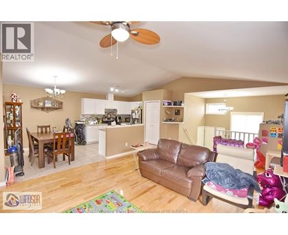 A living room with a brown leather couch and a ceiling fan.