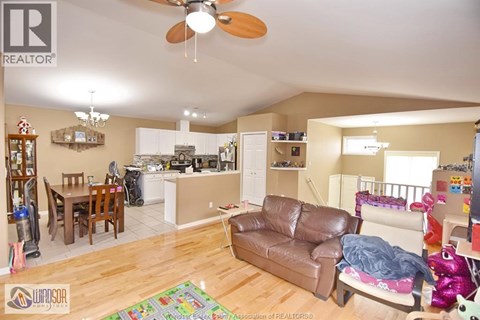 A living room with a brown leather couch and a ceiling fan.