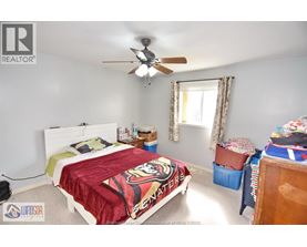 A bedroom with a bed covered in a "Spartans" blanket.