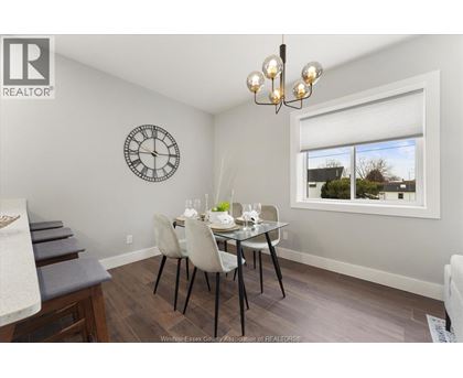 A dining room with a table set for two and a clock on the wall.