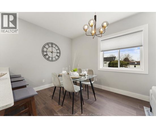 A dining room with a table set for two and a clock on the wall.