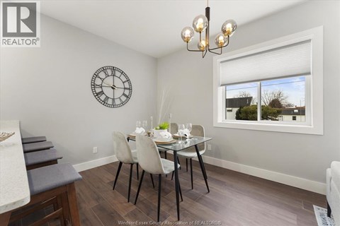 A dining room with a table set for two and a clock on the wall.