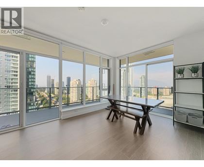 A spacious room with a table and bench, large windows, and a view of the city.