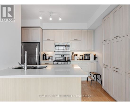 A modern kitchen with a stainless steel refrigerator, oven, and sink.