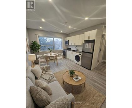 A well-lit, modern kitchen and living room with a grey sofa and wooden coffee table.