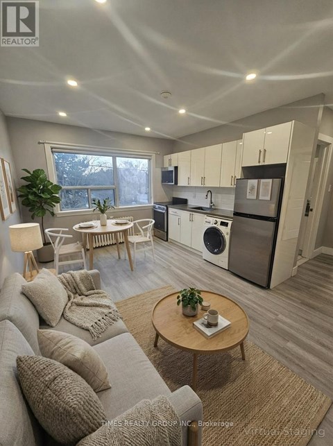 A well-lit, modern kitchen and living room with a grey sofa and wooden coffee table.