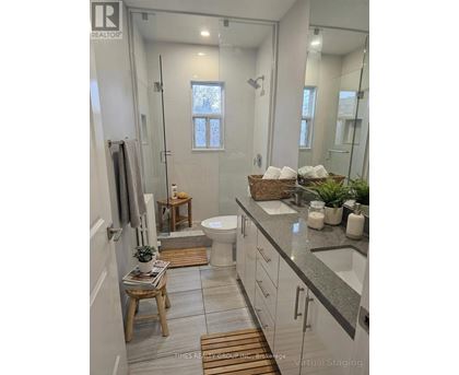 A bathroom with a glass shower stall and a toilet.