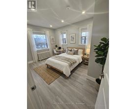 A bedroom with a large bed and a window with white curtains.