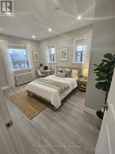 A bedroom with a large bed and a window with white curtains.
